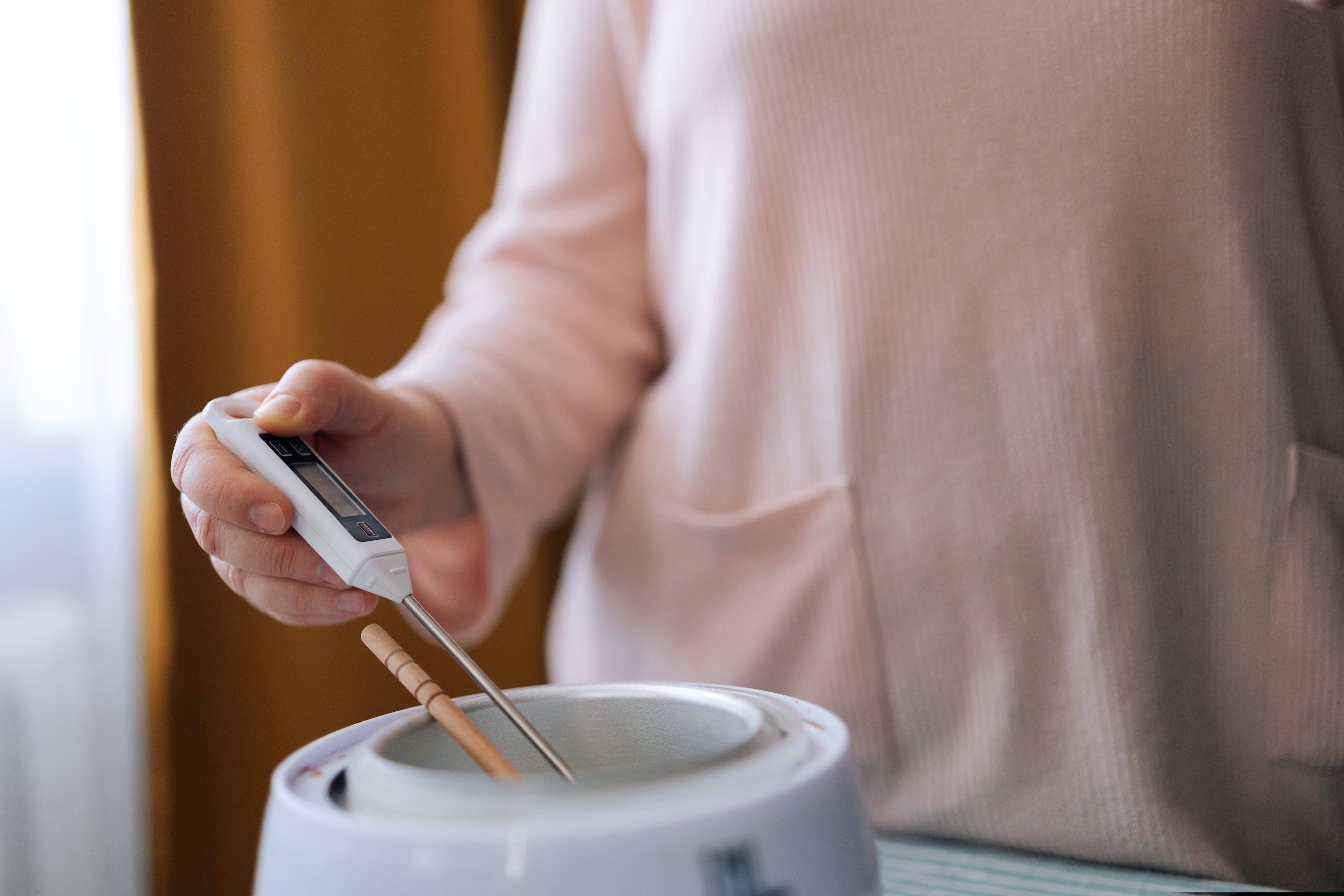 Woman holding thermometer in a melting pot 