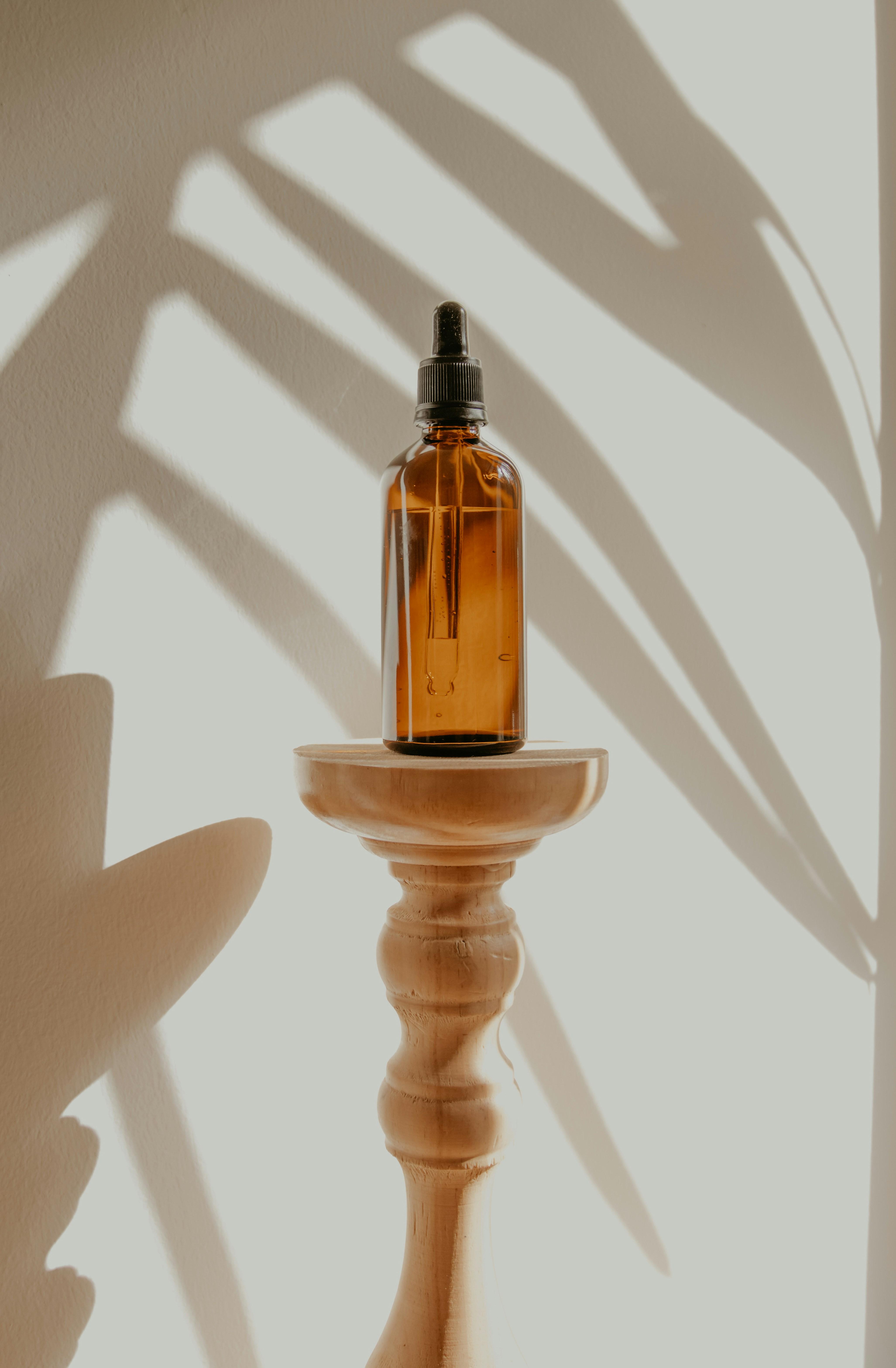 amber glass bottle with dropper top on a wooden pedastal