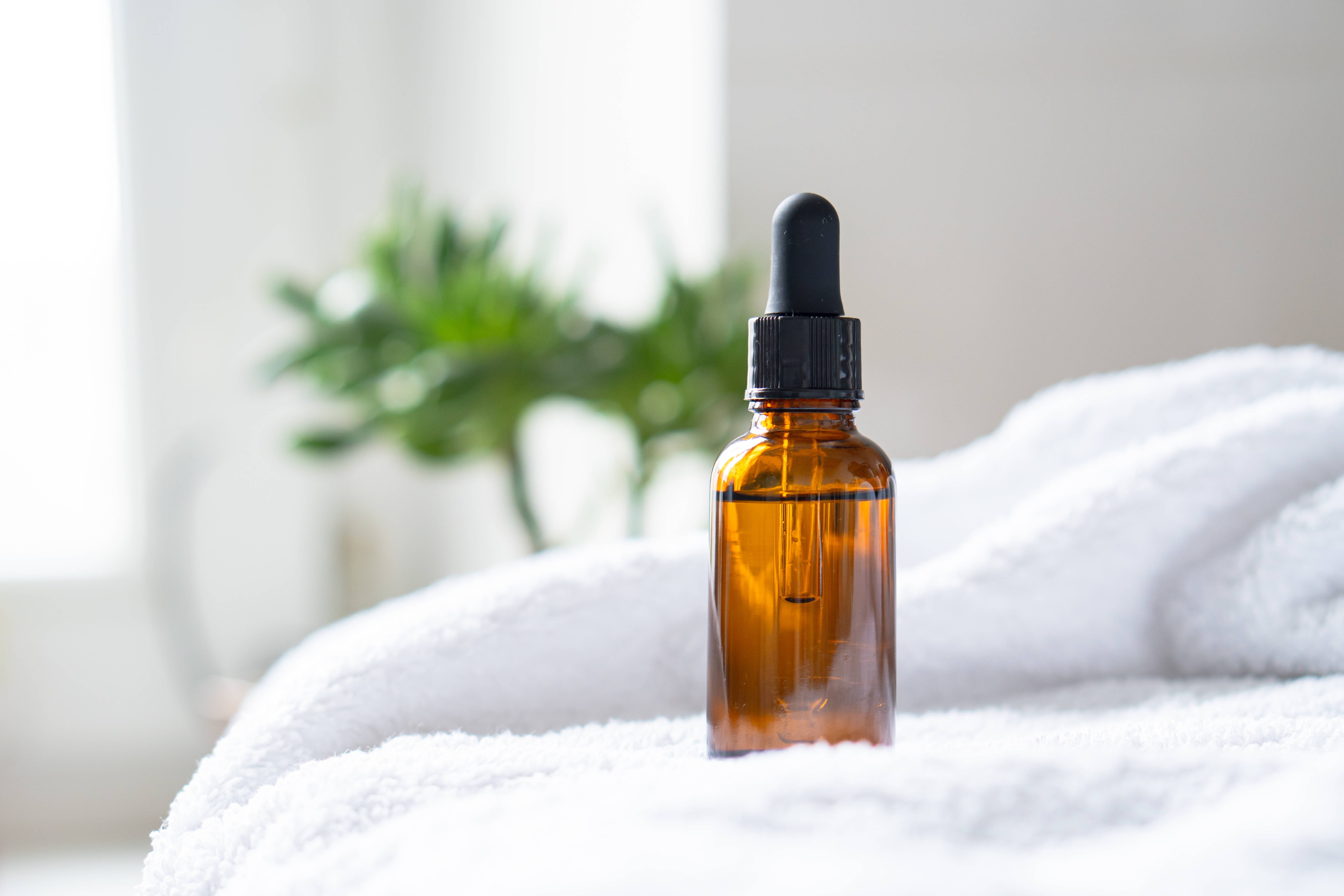 amber glass jar with black dropper top on a white towel
