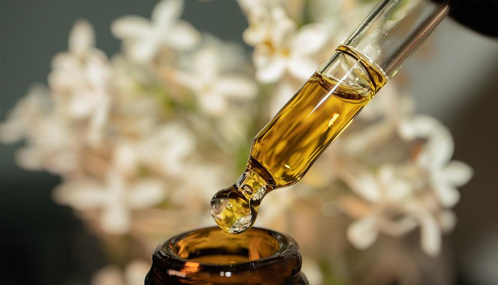 glass dropper filled with amber liquid over an amber bottle