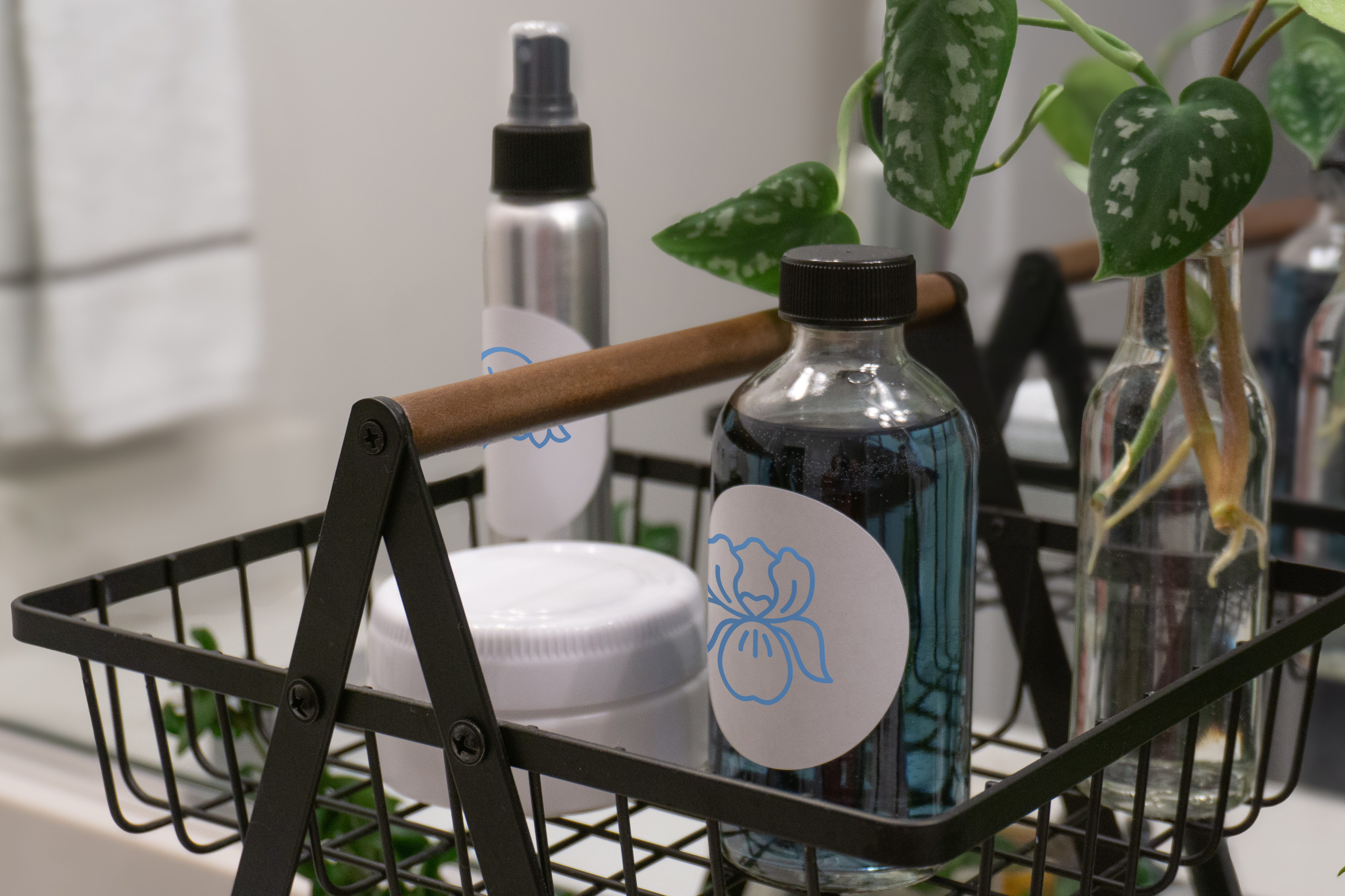A variety of glass, metal, and plastic bottles and jars in a wire basket in front of a bathroom mirror