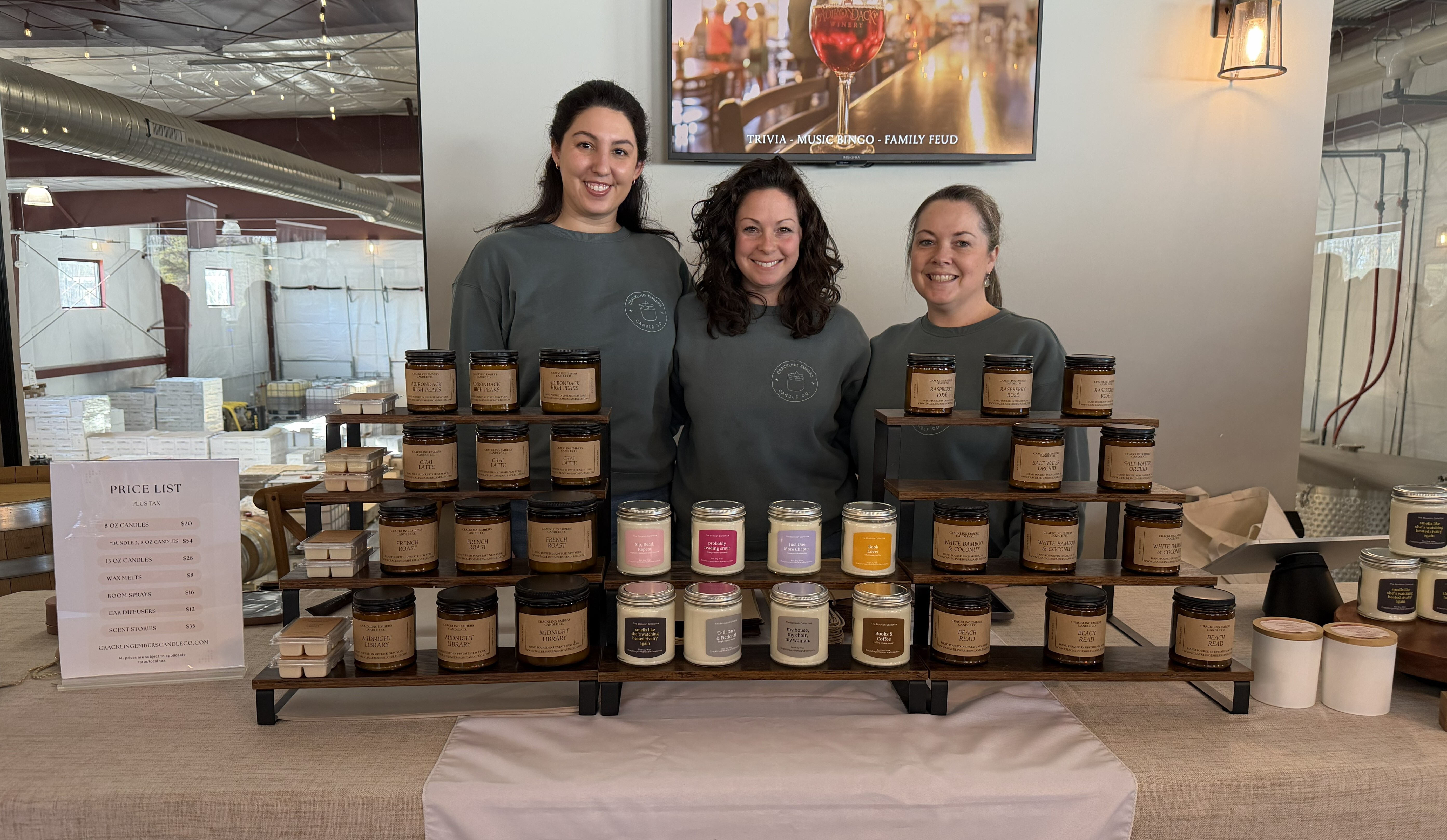 Crackling Embers Candle Co. founders standing behind their table of candles at an event