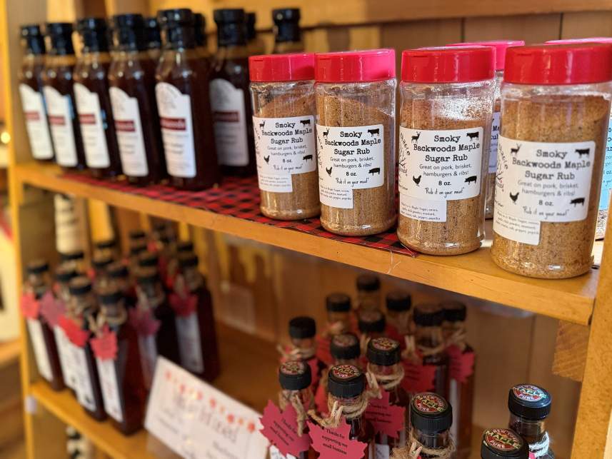 A selection of sauces, syrups, and rubs on wooden shelves