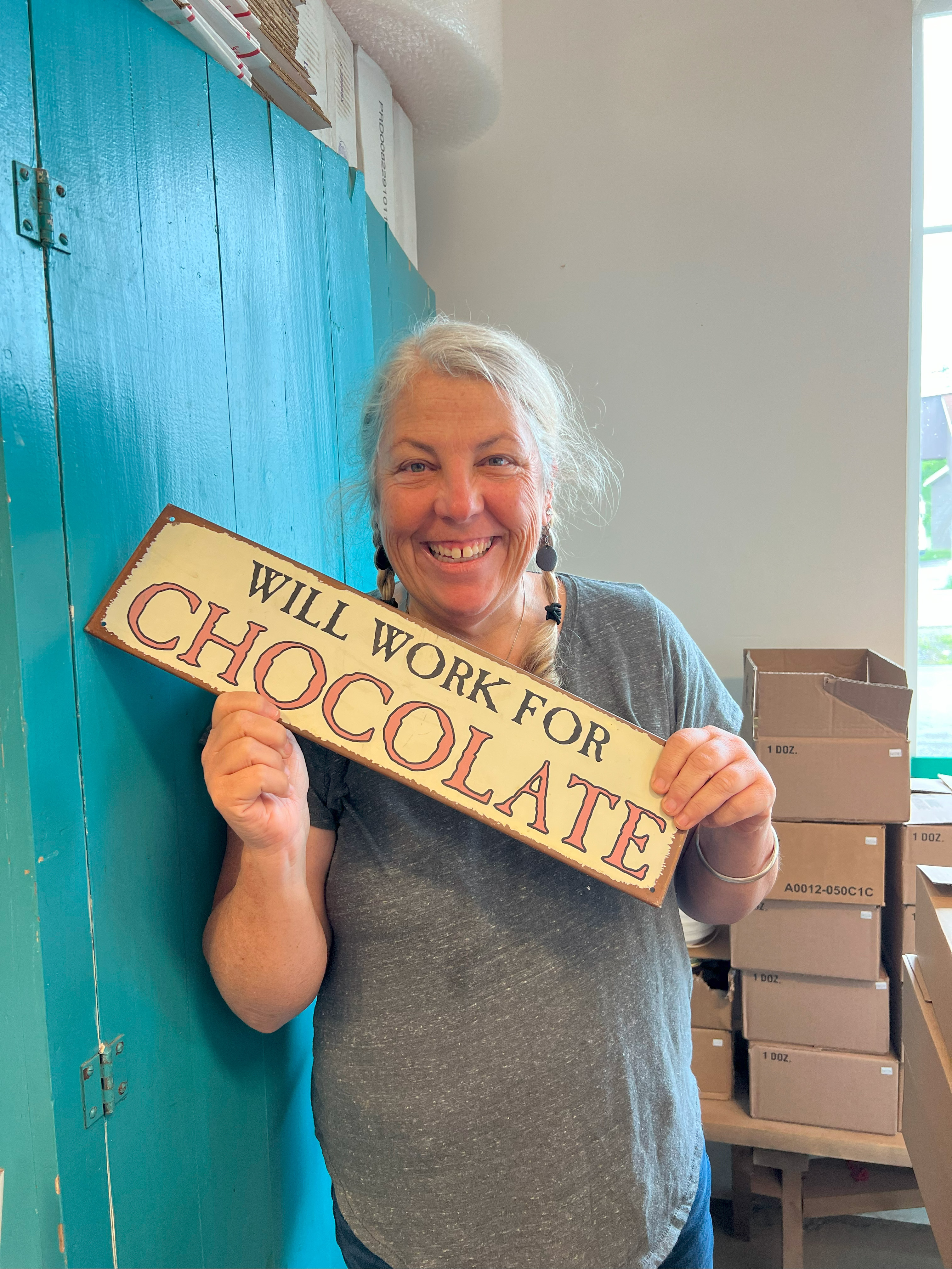 Katie Camarro holding a sign that says will work for chocolate