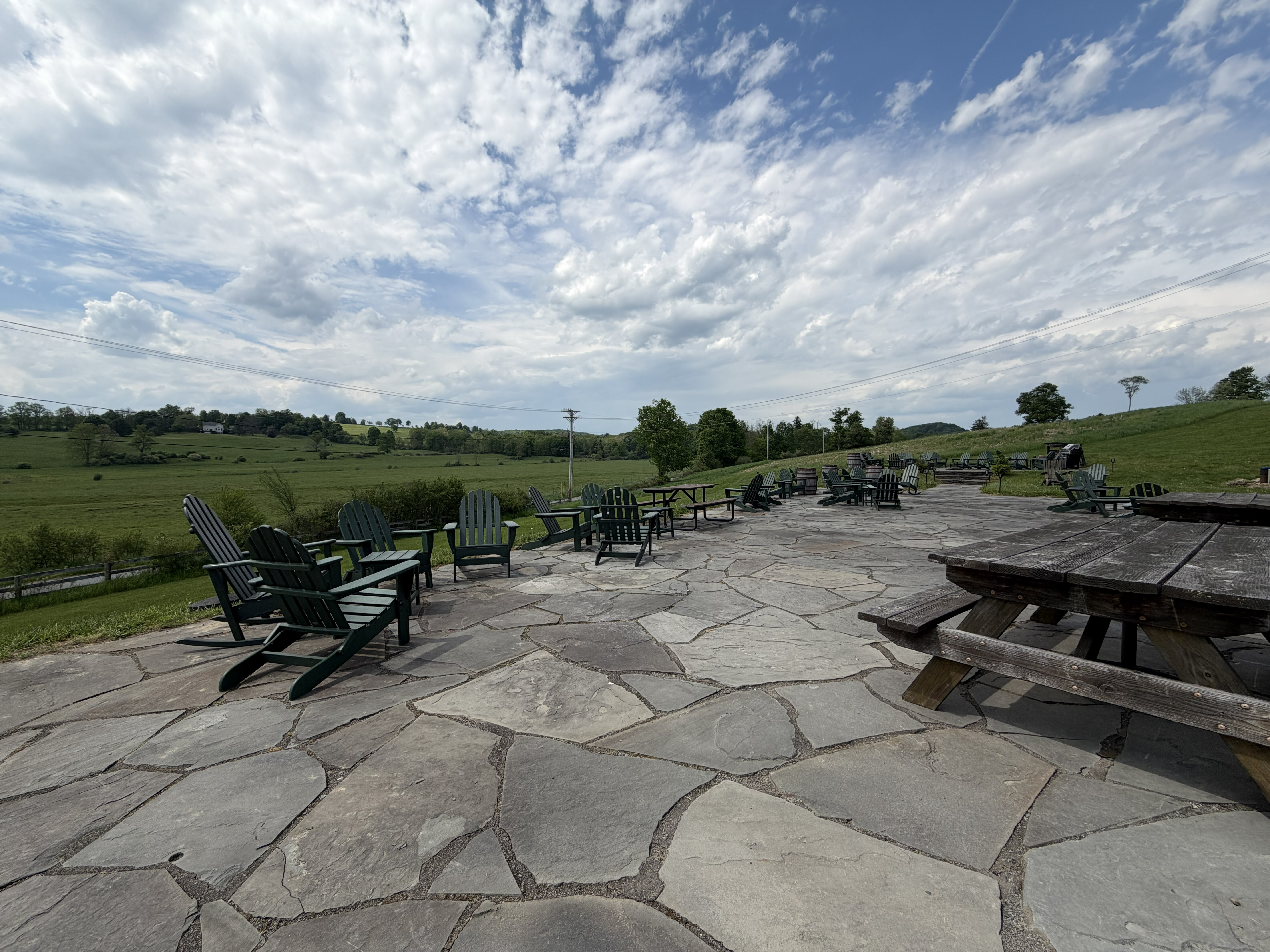 A stone patio with adirondack chairs overlooking farm fields