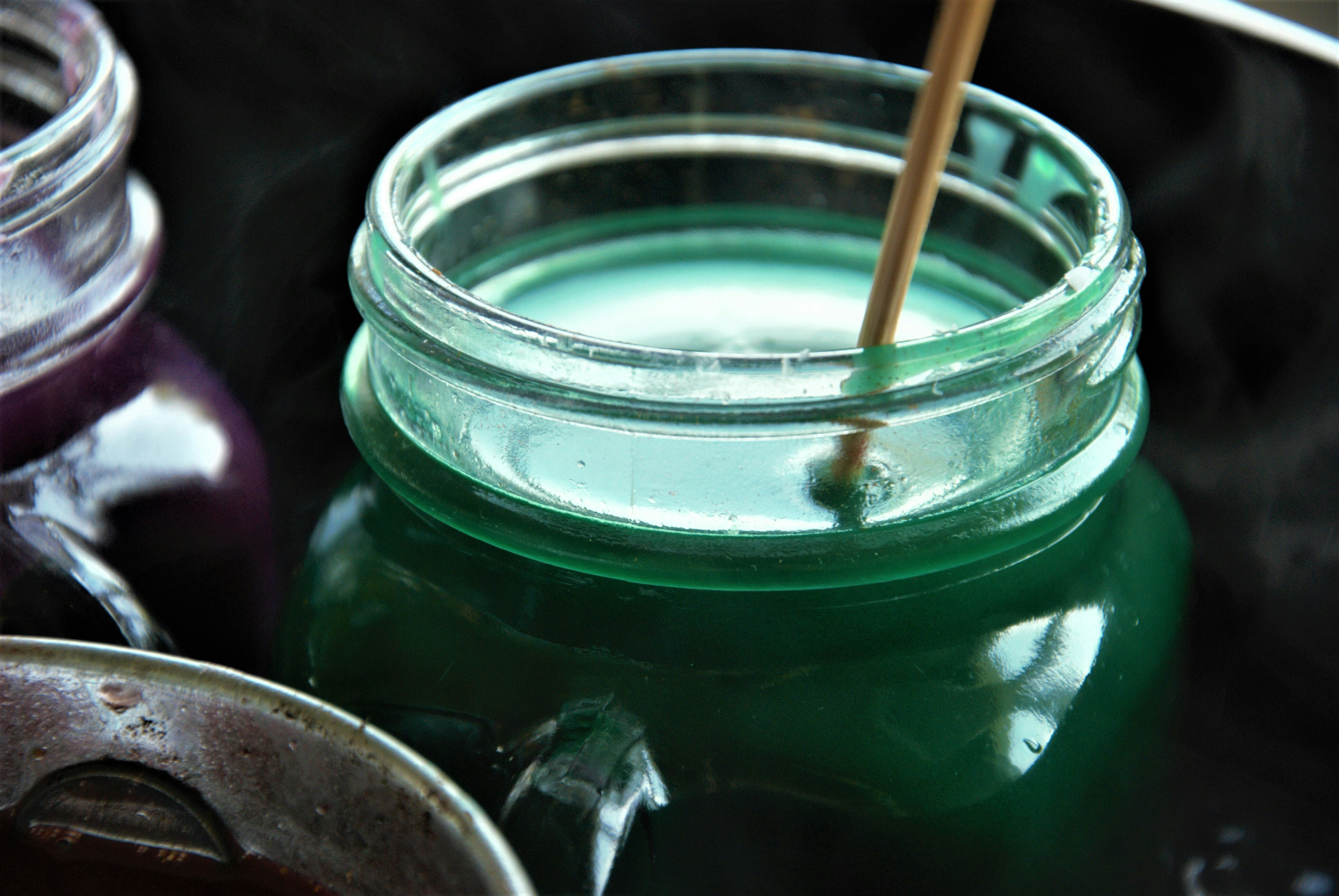Glass mason jar with handle filled with green candle wax